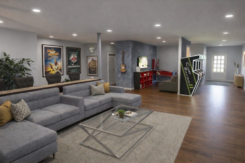 Game room with a sectional sofa, arcade cabinets and a bar beyond