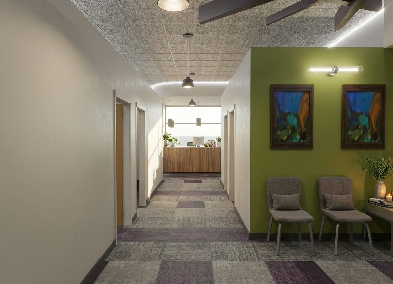 Corridor with a green accent wall, framed artwork and a pair of waiting chairs