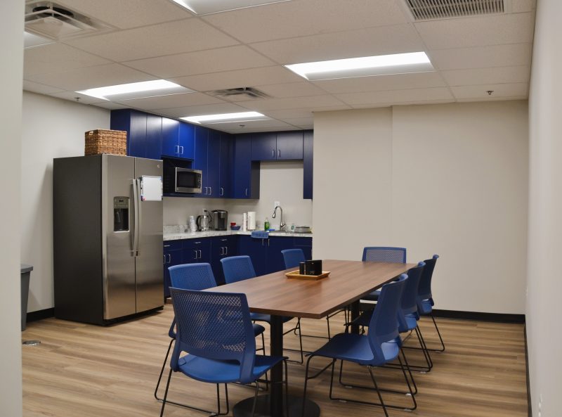 Staff break room with blue cabinetry and a communal table